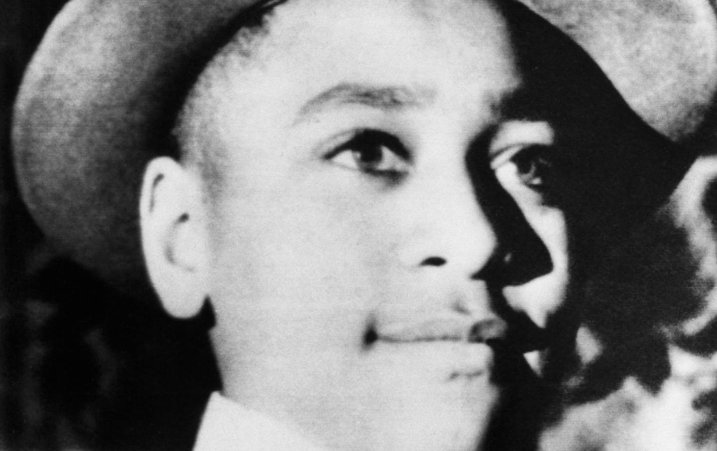 Emmett Till looks into the distance. He is wearing a hat.