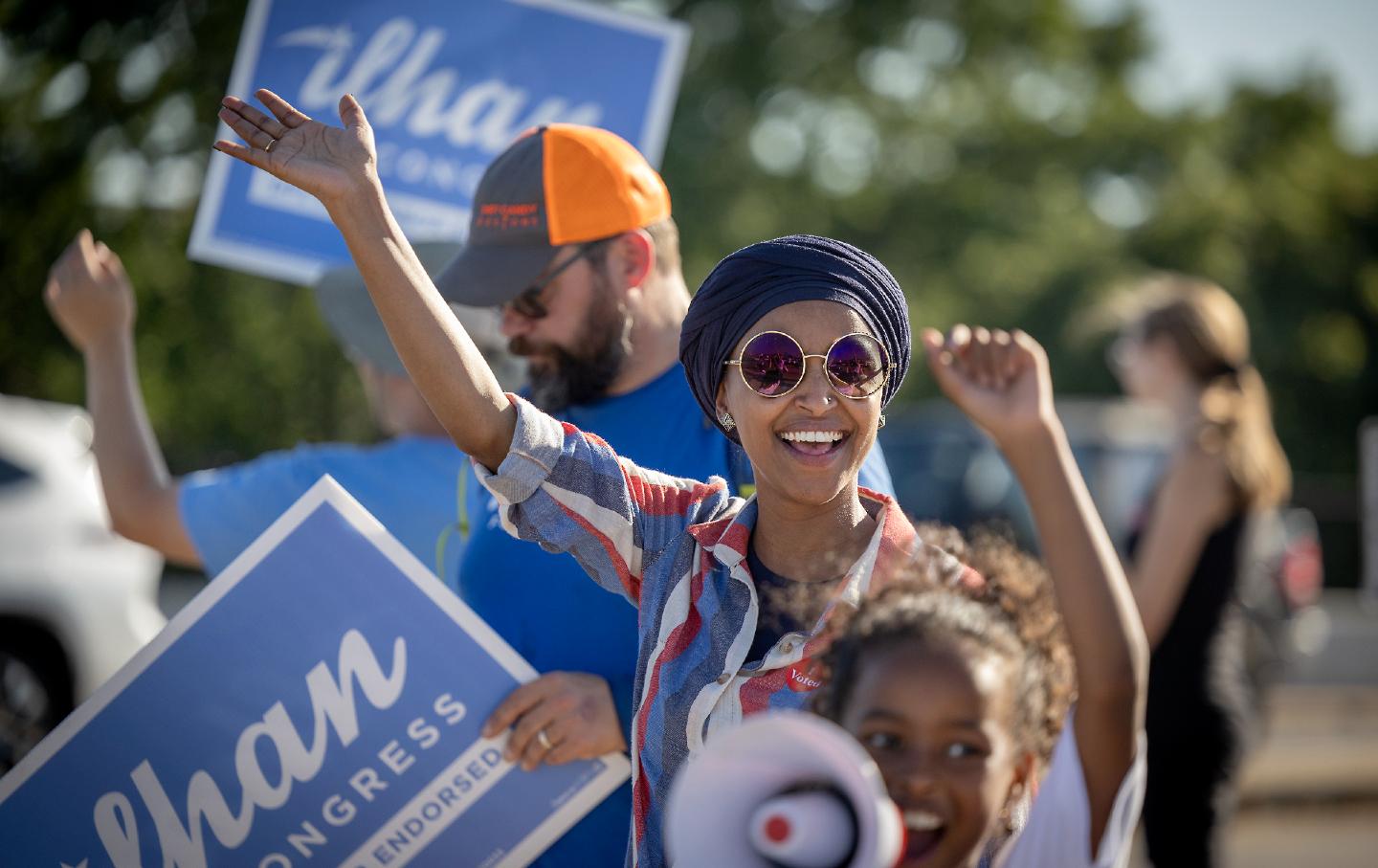 Rep. Ilhan Omar waves to passersby during a voter engagement event in Minneapolis.
