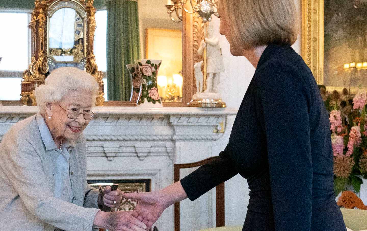 Queen Elizabeth shakes hands with newly elected leader of the Conservative party Liz Truss in an opulent room in Balmoral Castle.