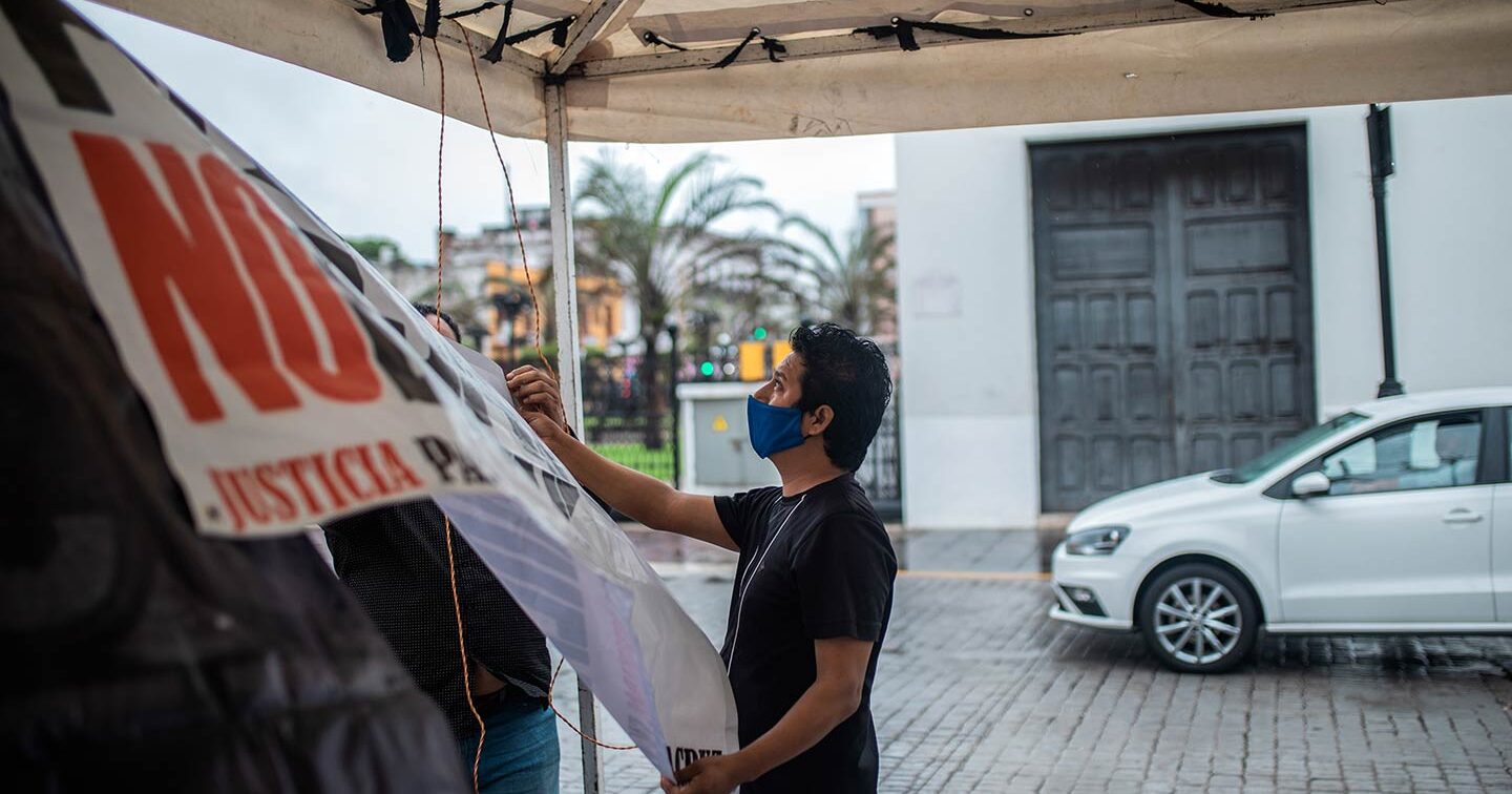 Jorge Sanchez hangs a banner wearing a blue face mask.