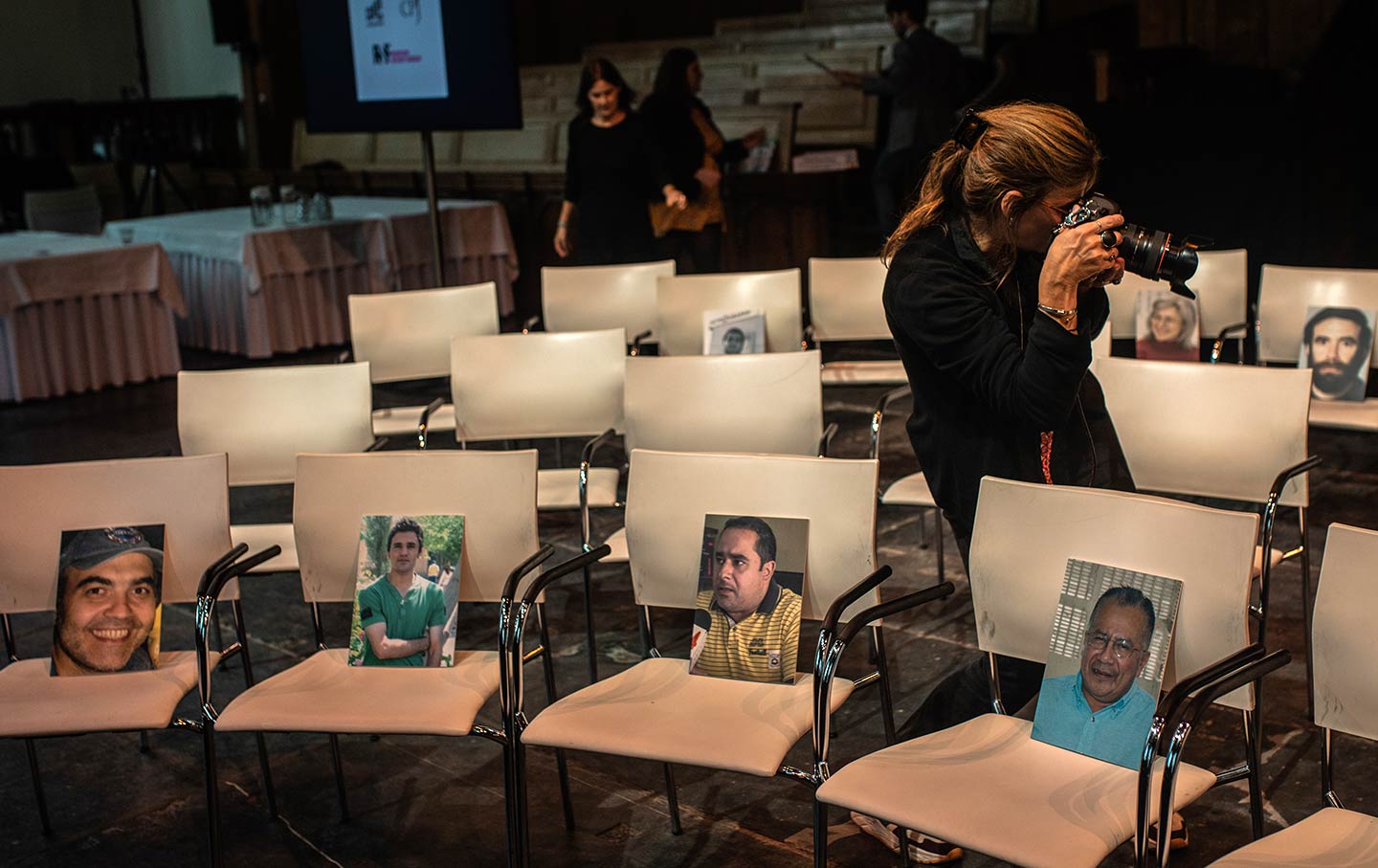 A photographer takes photos of chairs with images of assassinated journalists on them.
