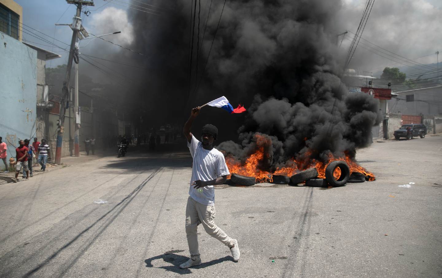 A man waves a Russian national flag next to a burning barricade protesting Haitian Prime Minister Ariel Henry.