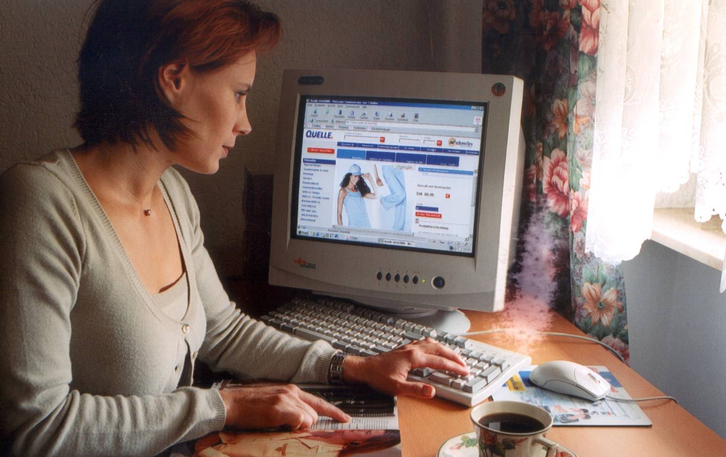 A young woman has a cup of coffee while shopping on the Internet in the 1990s.
