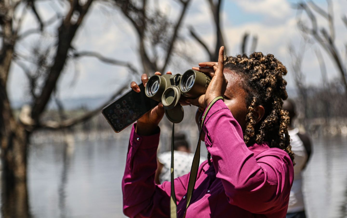 A journalist using binoculars during an event to understand the impact of climate change on biodiversity in Kenya's Lake Nakuru National Park