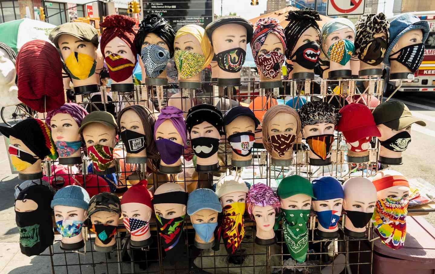 A street stall displays cloth masks on mannequin heads.