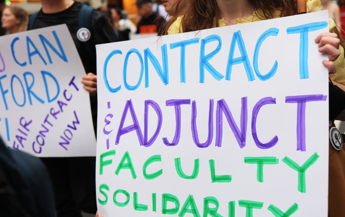 Members of NYU’s Adjunct Faculty union march near Union Square. In the photo, one member holds a sign reading 