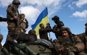 Ukrainian soldiers adjust flag