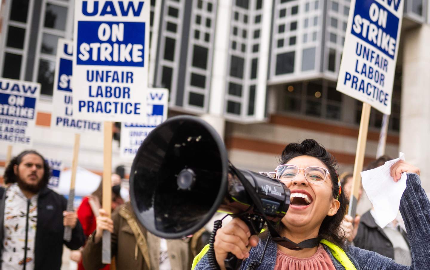 A PhD student with a megaphone leads a picket.