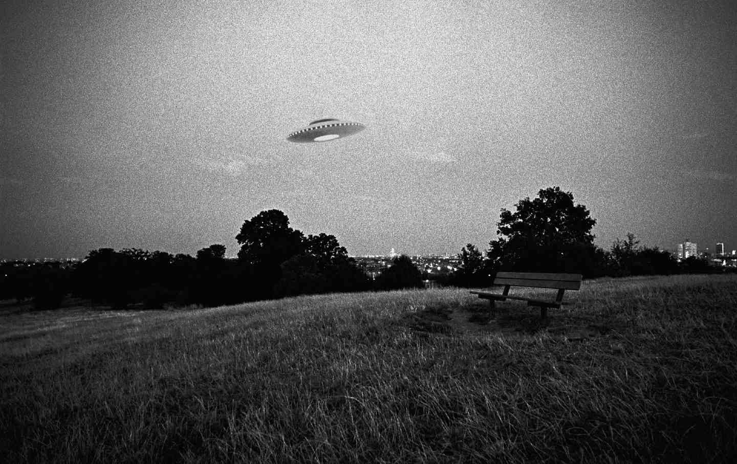 A digital composite of a UFO flying above an urban park.