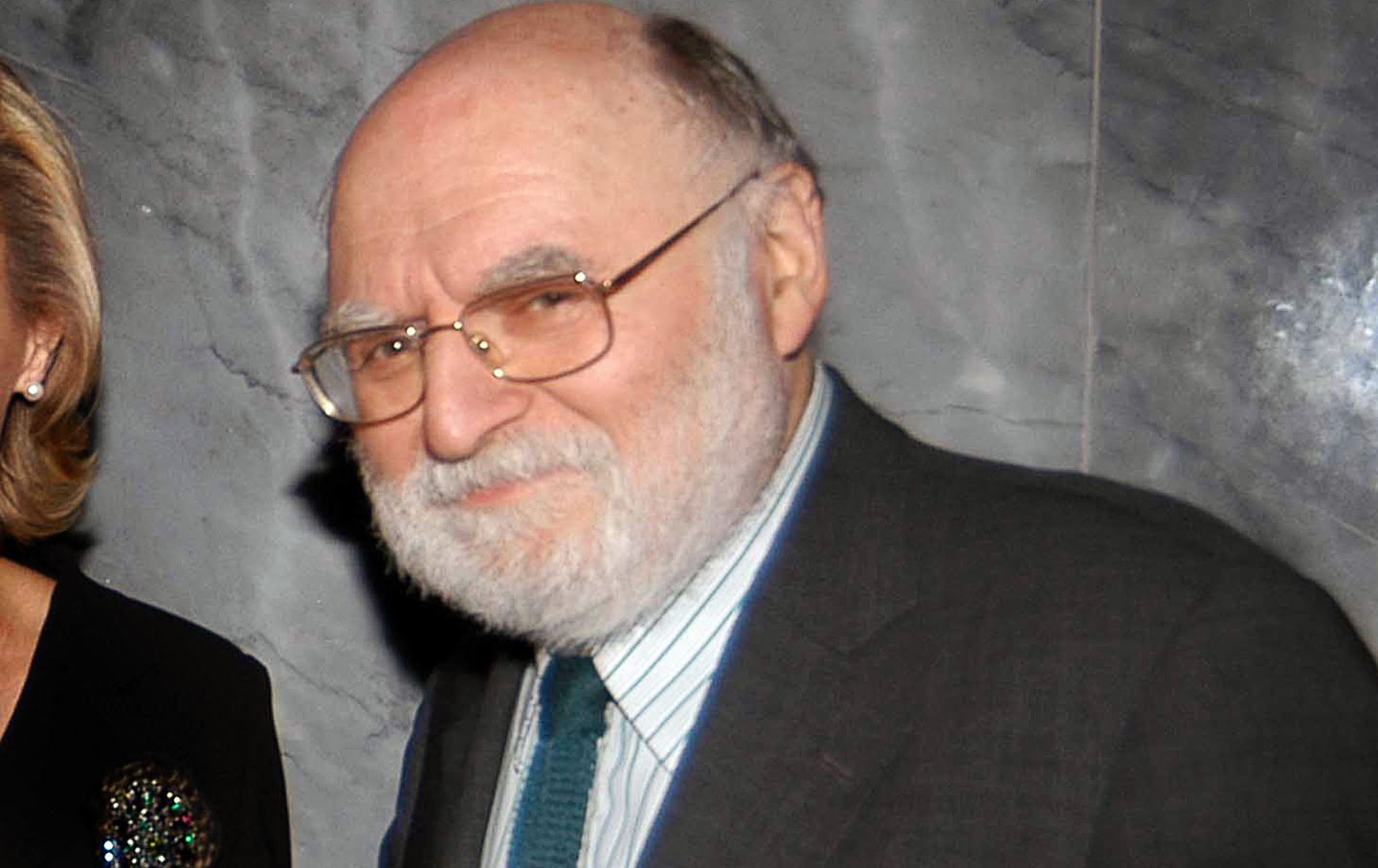 Victor Navasky looks at the camera wearing green knit tie and suit.