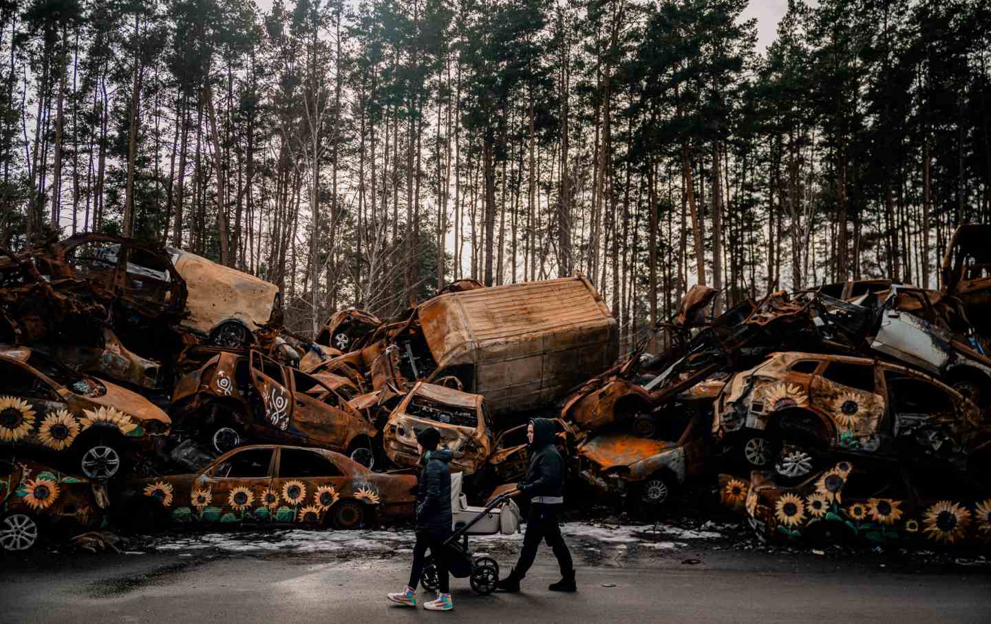 A woman pushes a baby stroller while walking in a cemetery in Irpin, near Kyiv on February 16, 2023.