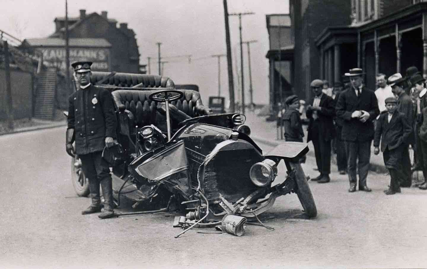 A police officer stands beside an automobile involved in an accident,