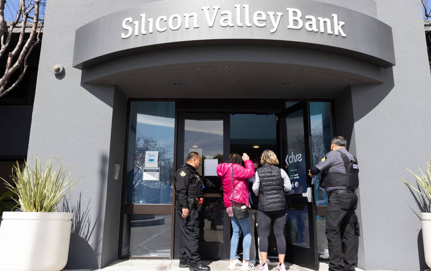 People outside Silicon Valley Bank with security guards allowing them in.