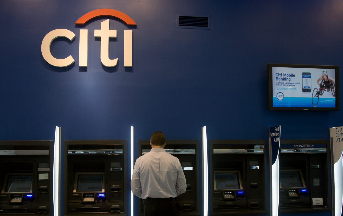 A man does a banking transaction at a Citibank ATM fast cash machine.