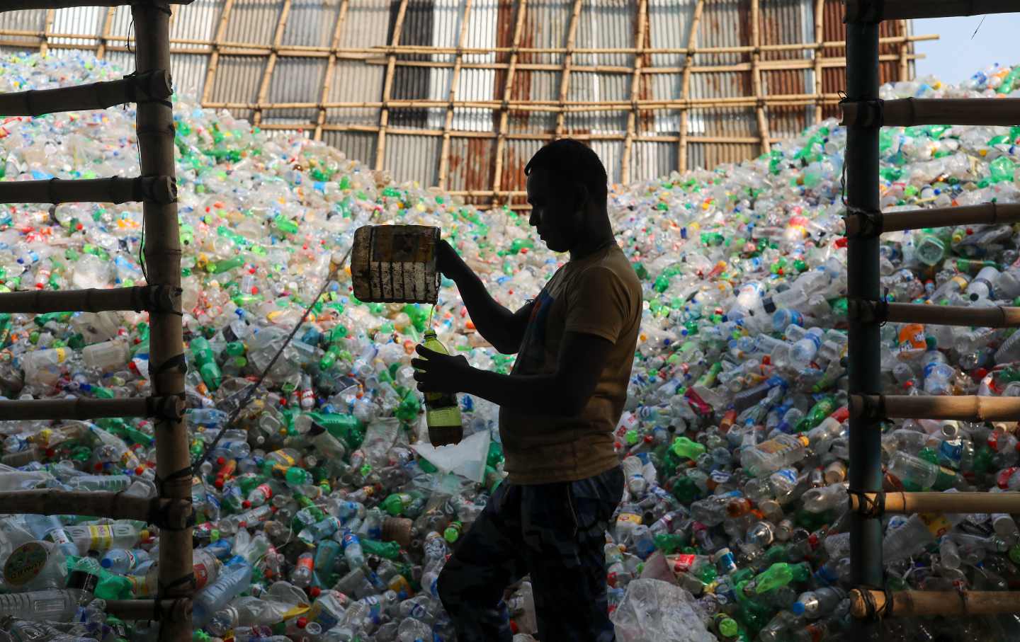 Man pours liquid into a bottle in front of a pile of bottles