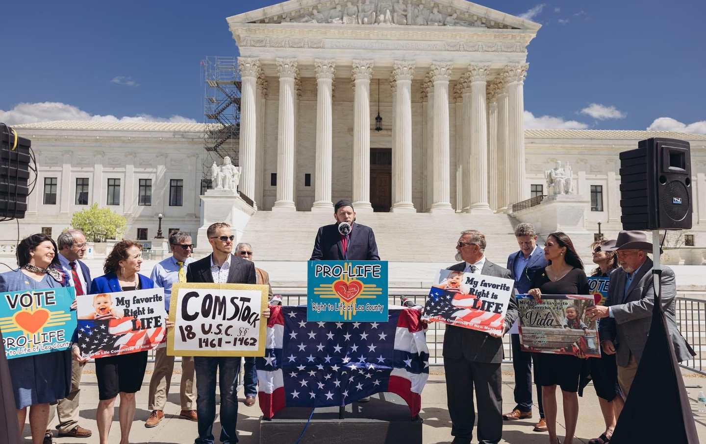 Approximately 15 anti-abortion advocates stand outside the Supreme Court with signs opposing abortion.