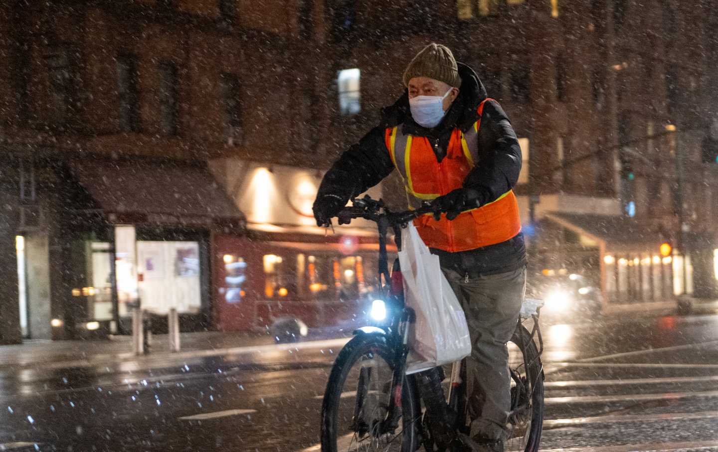 A food delivery driver on a bicycle rides in the snow on January 28, 2022 in New York City.