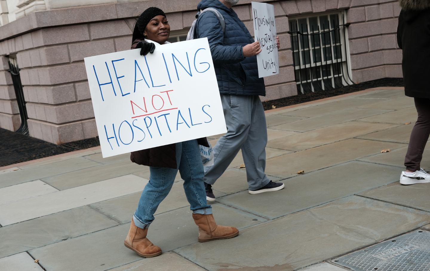 woman hold sign protesting Eric Adams policy on mental health