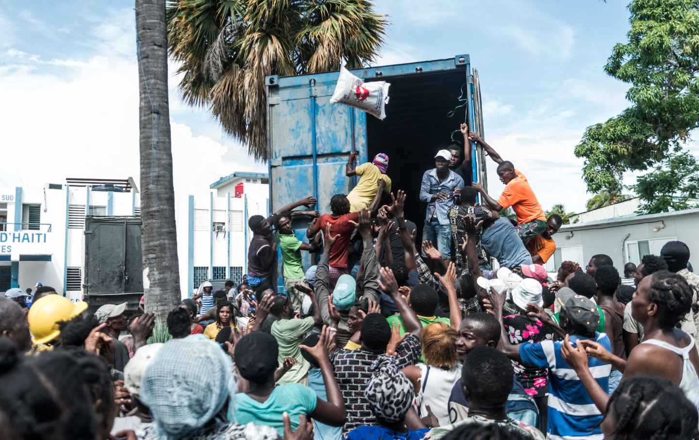 a man throws a bag of rice off a truck in Haiti