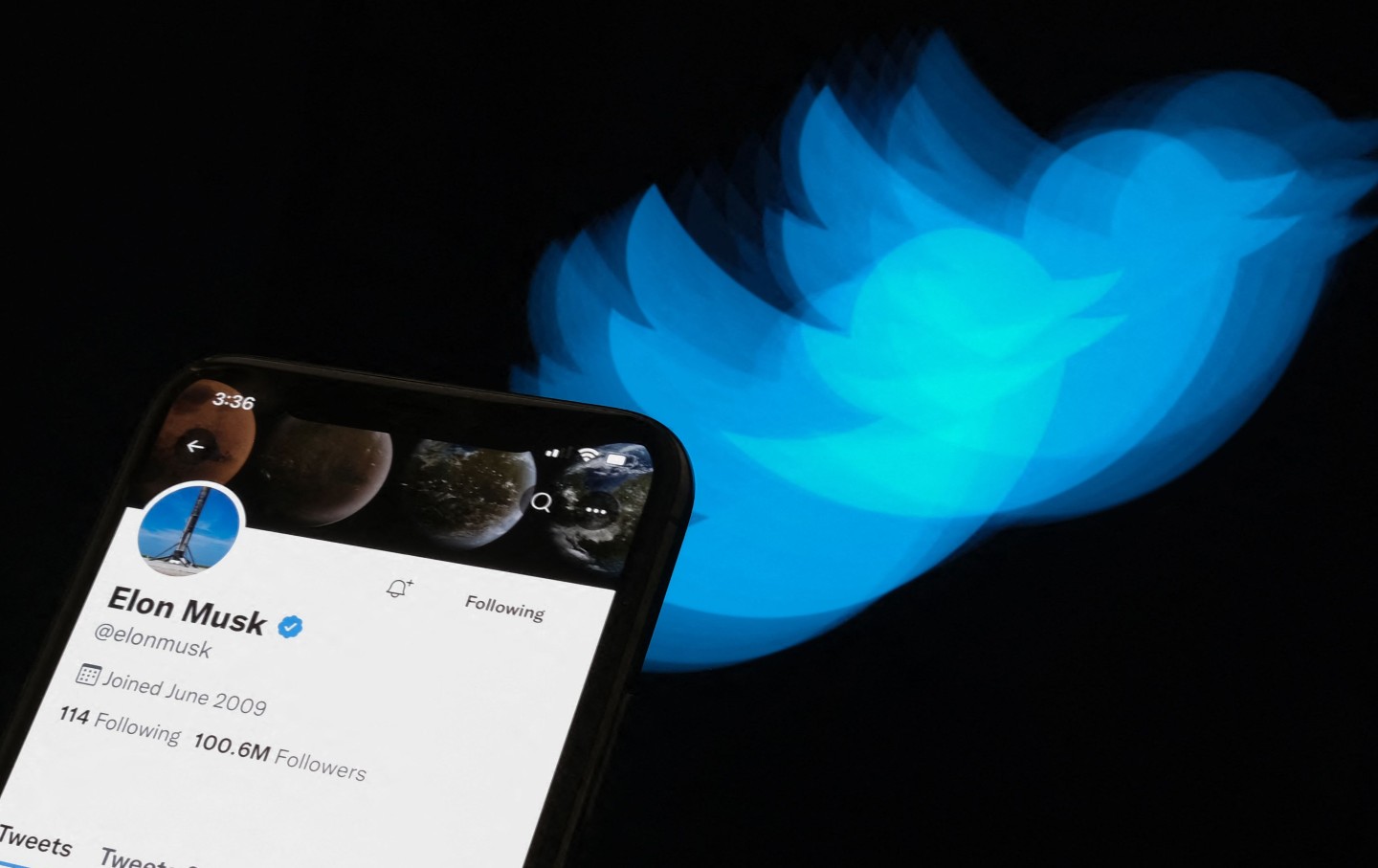 This illustration photo taken on July 8, 2022 shows Elon Musk's Twitter page displayed on the screen of a smartphone with Twitter logo in the background in Los Angeles. - Elon Musk pulled the plug on his deal to buy Twitter on July 8, 2022, accusing the company of