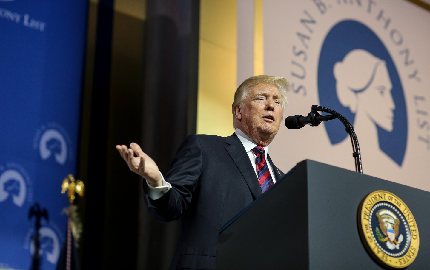 President Donald Trump at a lectern in front of a large poster depicting the logo and name of the Susan B. Anthony List.