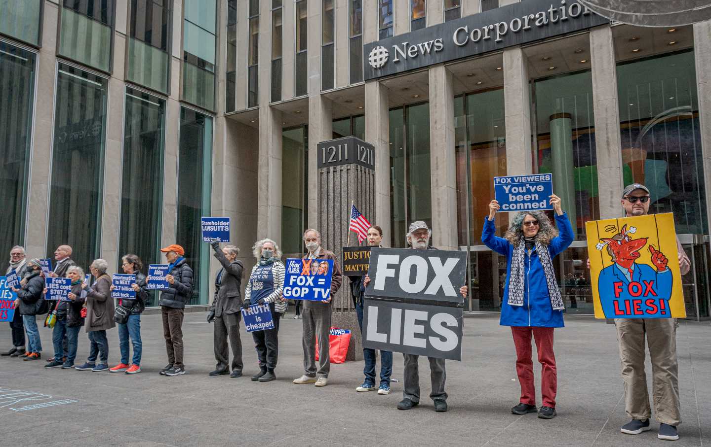 A line of protesters holding signs including 