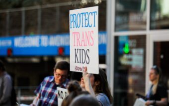 A protester holds a sign that reads, ''Protect trans kids'' at a demonstration condemning Ron DeSantis during a Republican fundraising event in Houston, Texas on March 3, 2023.