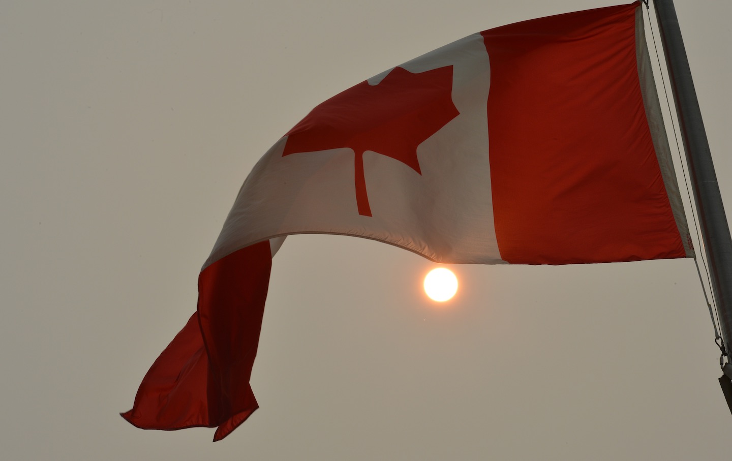 A view of the Canadian flag in front of the moon as smoke from forest fires reached the center of Ottawa again on June 25, 2023.