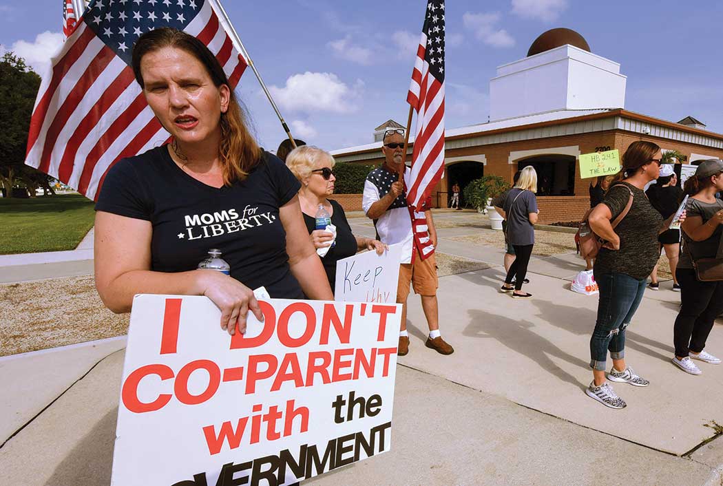 The attack on trans kids is backed by groups like Moms for Liberty, shown here protesting in Viera, Fla.