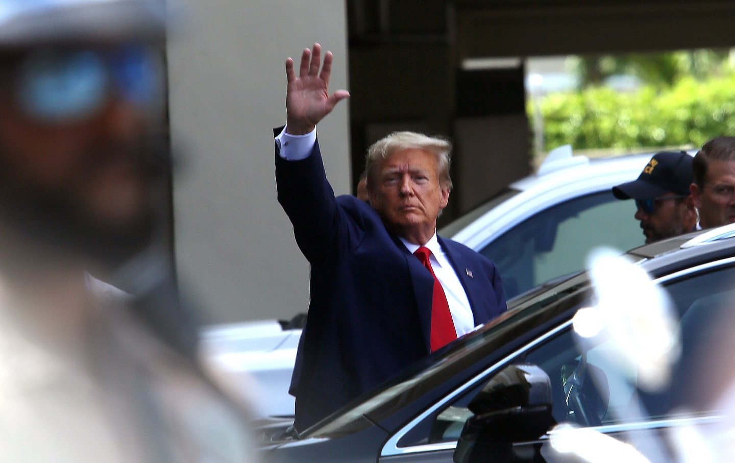 Donald Trump waving while getting into a car.