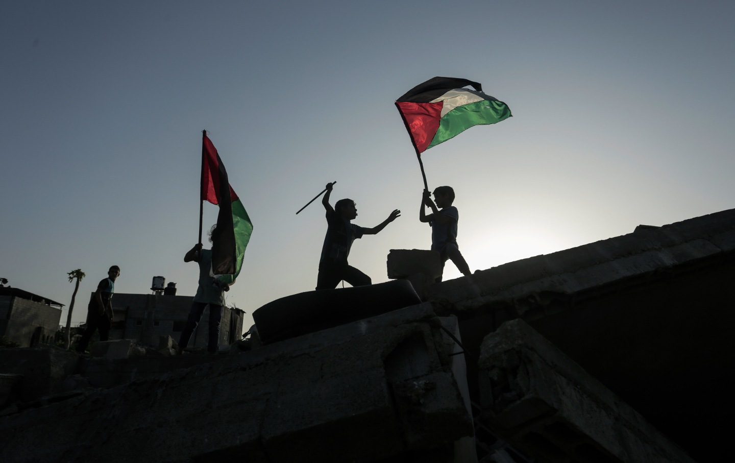 Kids wave Palestinian flags amidst the ruins of their destroyed home following Israeli raids on the town of Beit Lahiya in the northern Gaza Strip.