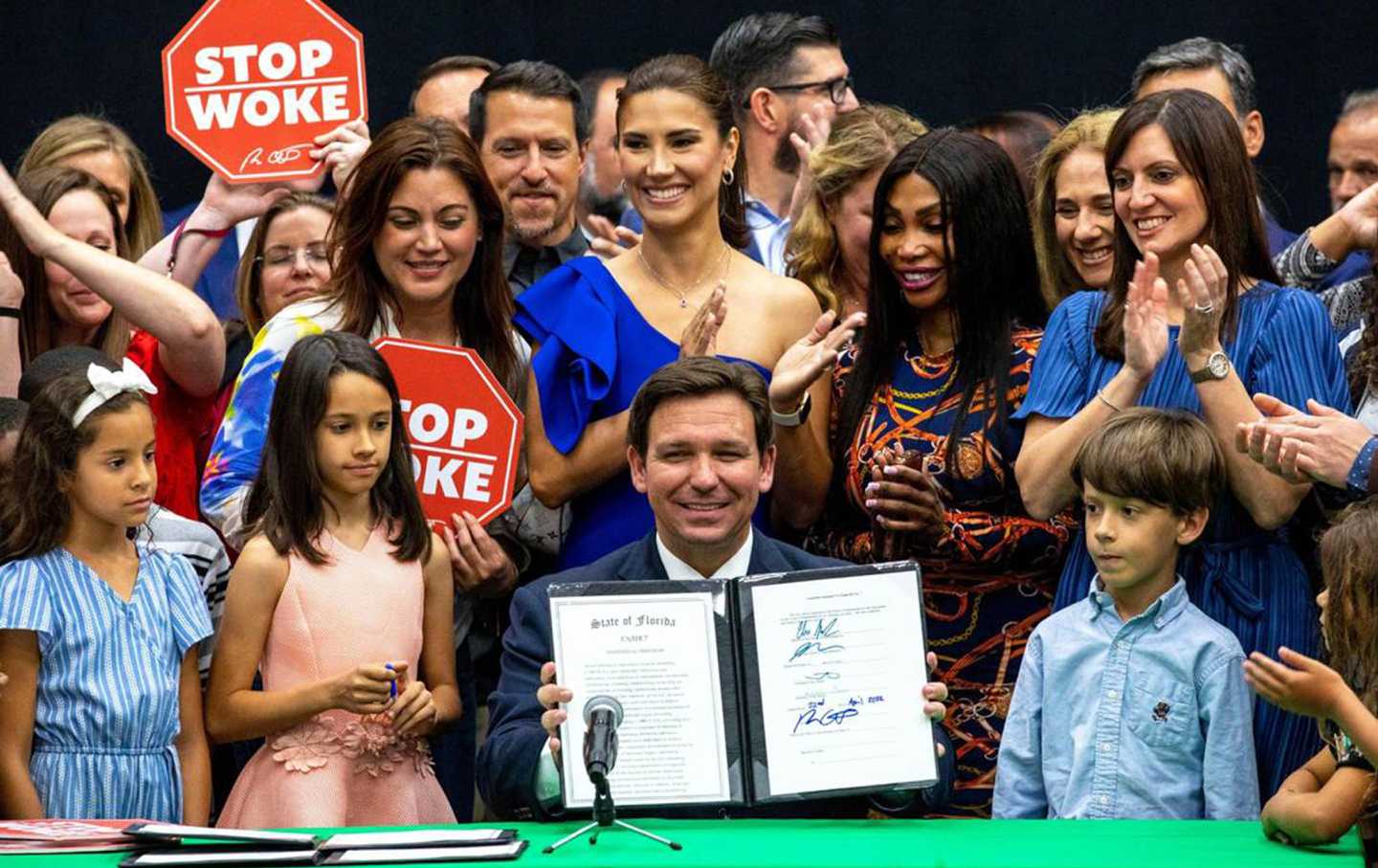 Ron DeSantis at center, surrounded by children and adults holding 