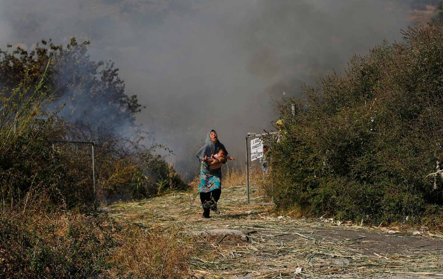A migrant holds her baby as she runs to avoid a fire on the northeastern island of Lesbos, Greece, on September 12, 2020.