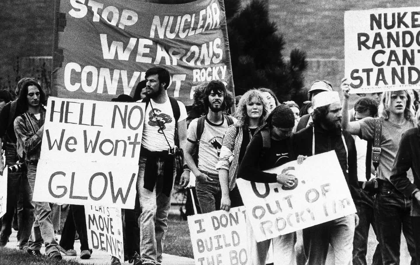 Black and white photo of young people protesting against nuclear weapons, holding sign that reads 'stop nuclear weapons'