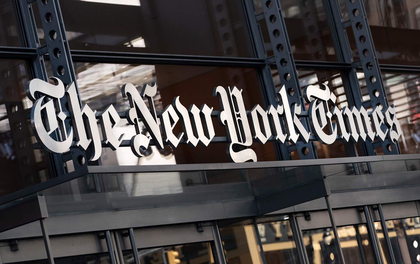 The logo of “The New York Times” hangs above the entrance to its building.