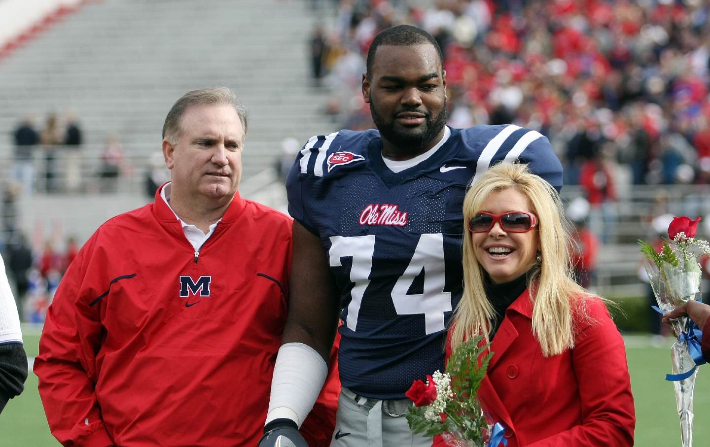Michael Oher and the Tuohys, who are portrayed in the film The Blind Side, stand on the field before an Ole Miss game.