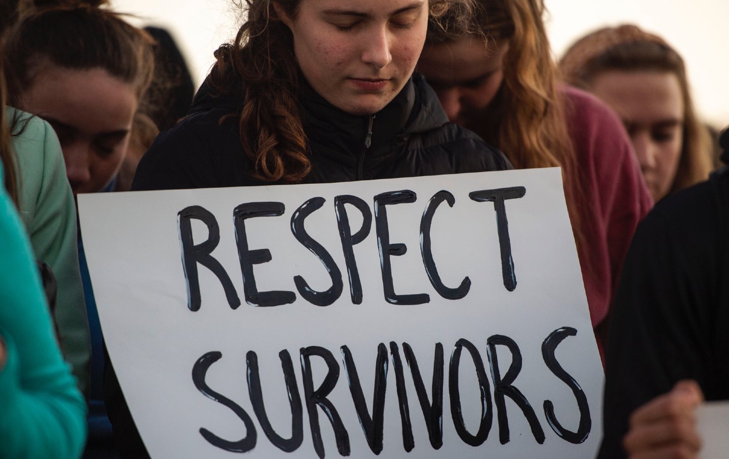 Young person holds a poster that reads "respect survivors" at a 2021 campus rally