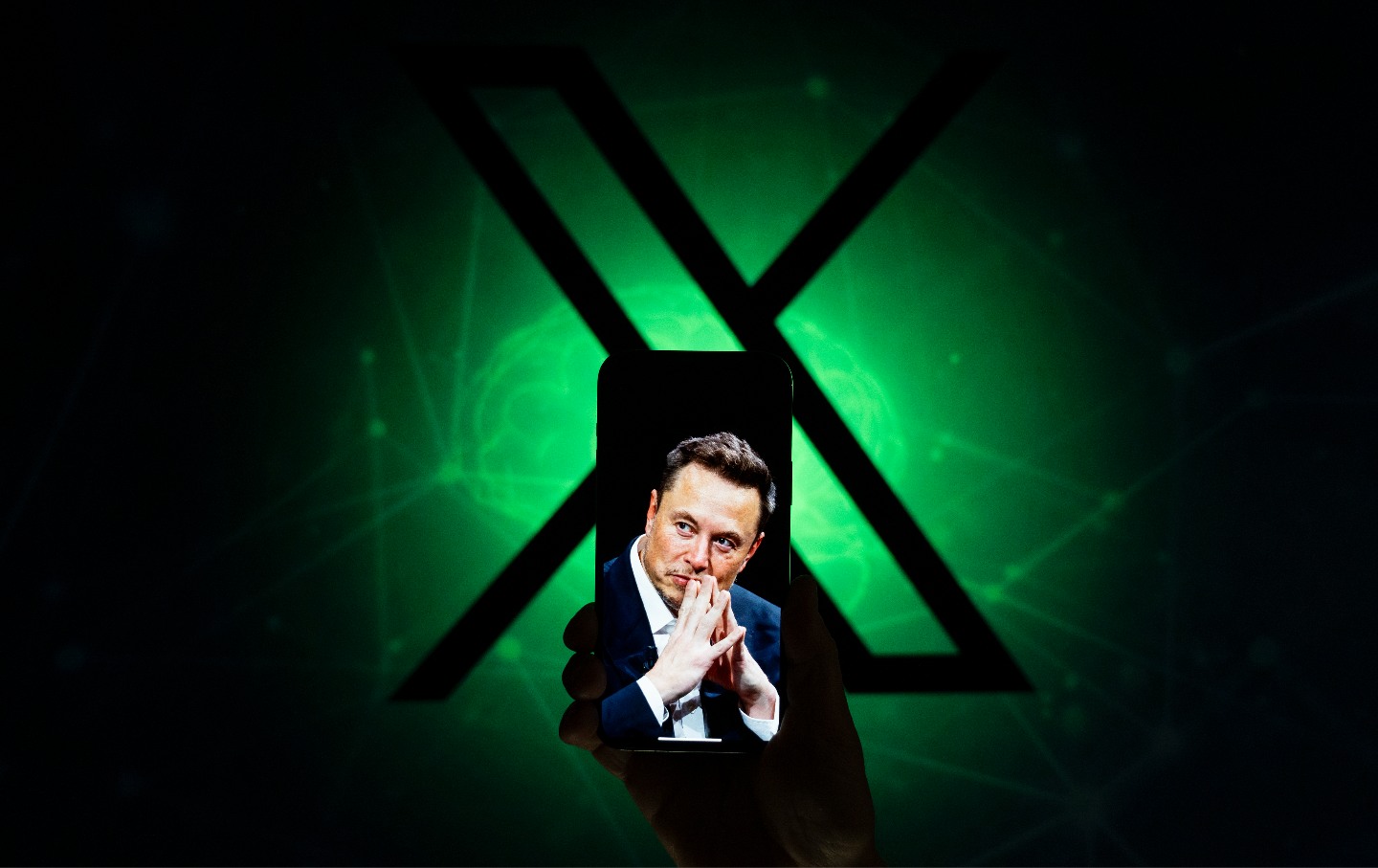 An effigy of Elon Musk is seen on the screen of a mobile device with the X logo in the background.