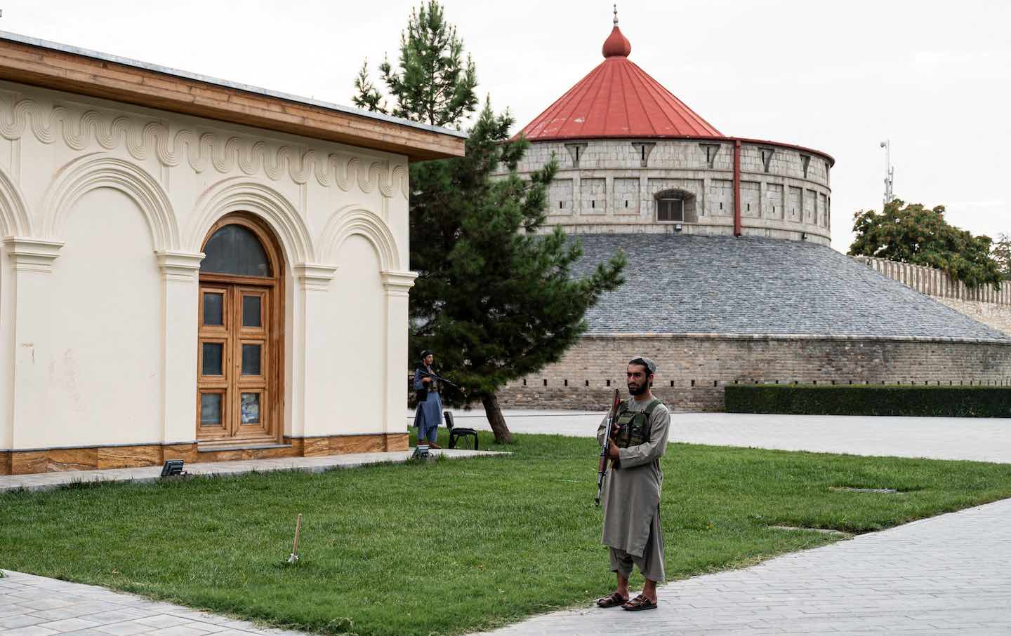 Taliban fighters stand guard outside the former presidential palace in Kabul on August 13, 2022.