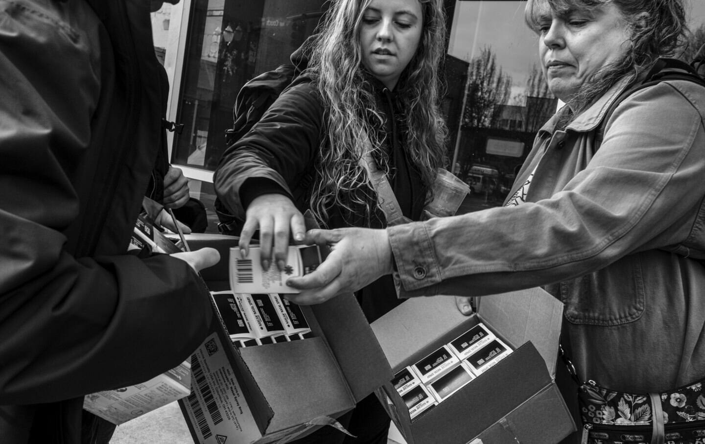 A black and white photo of two people handing out Narcan.