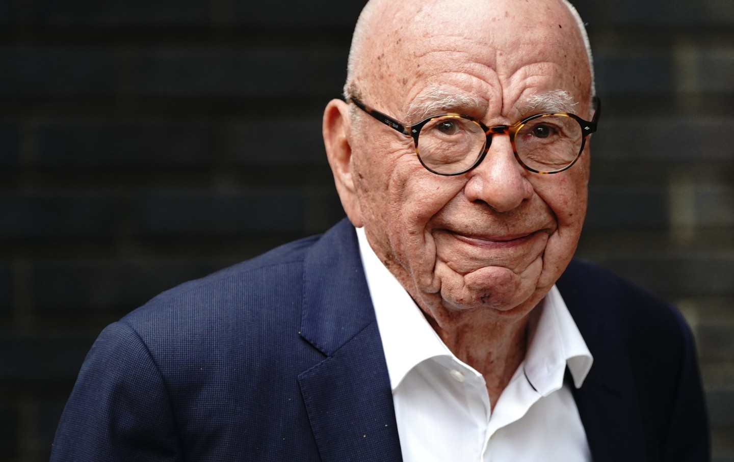 A close-up photo of Rupert Murdoch in a navy suit jacket and white shirt.
