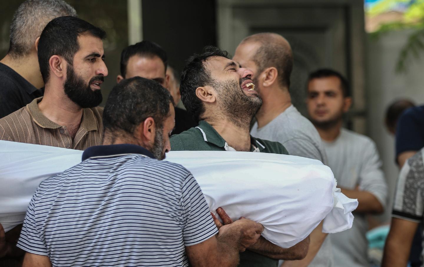 Ooutside the morgue of al-Shifa hospital in Gaza City, a Palestinian man weeps while carrying the body of one of the victims killed by Israeli air strikes.