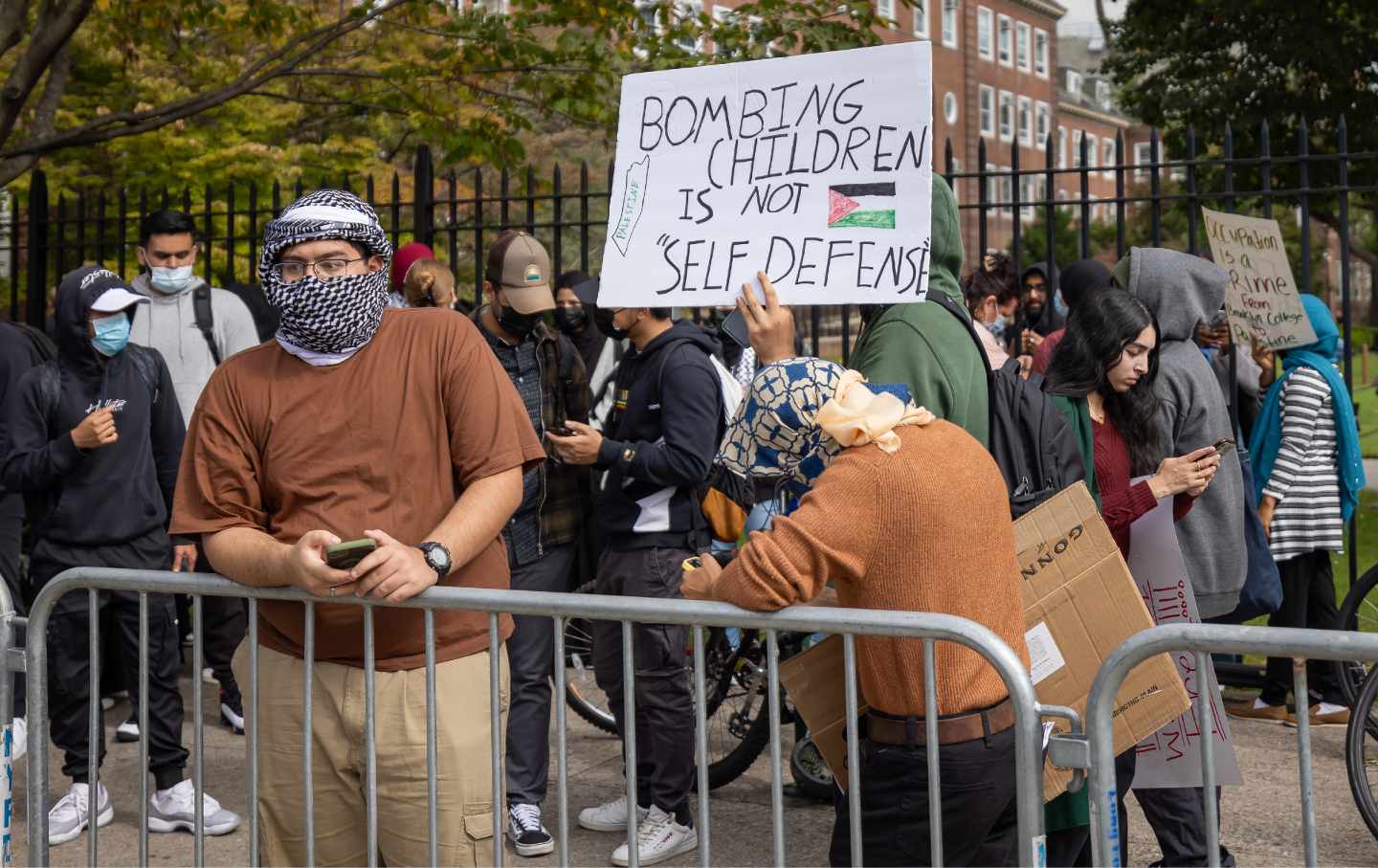 Students from Brooklyn College and supporters hold signs during a pro-Palestinian demonstration at the entrance of the campus.