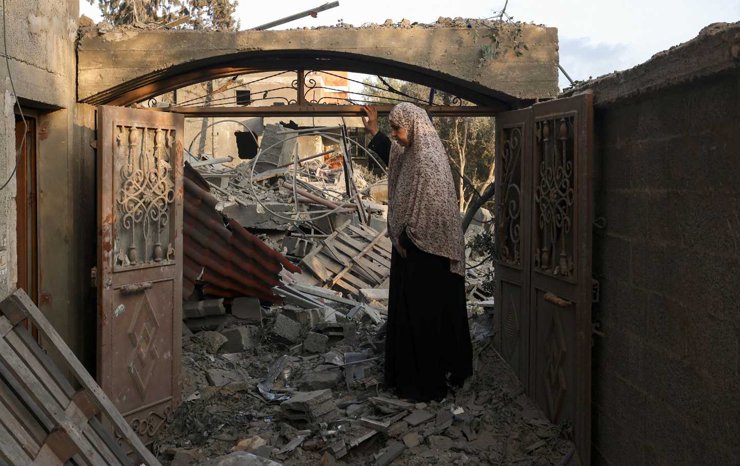 A woman inspects the damage to her home after Israeli strikes on the Rafah camp in the southern Gaza Strip on October 14, 2023.