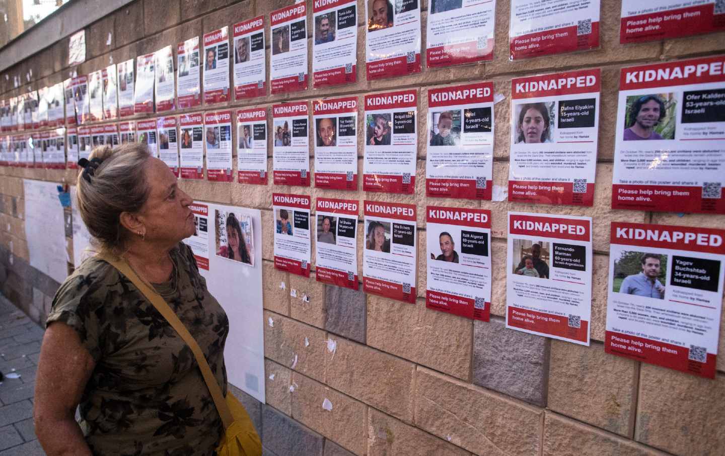 A woman looks at a wall with photos of hostages kidnapped and taken to Gaza by Hamas during its October 7 attack on Israel.