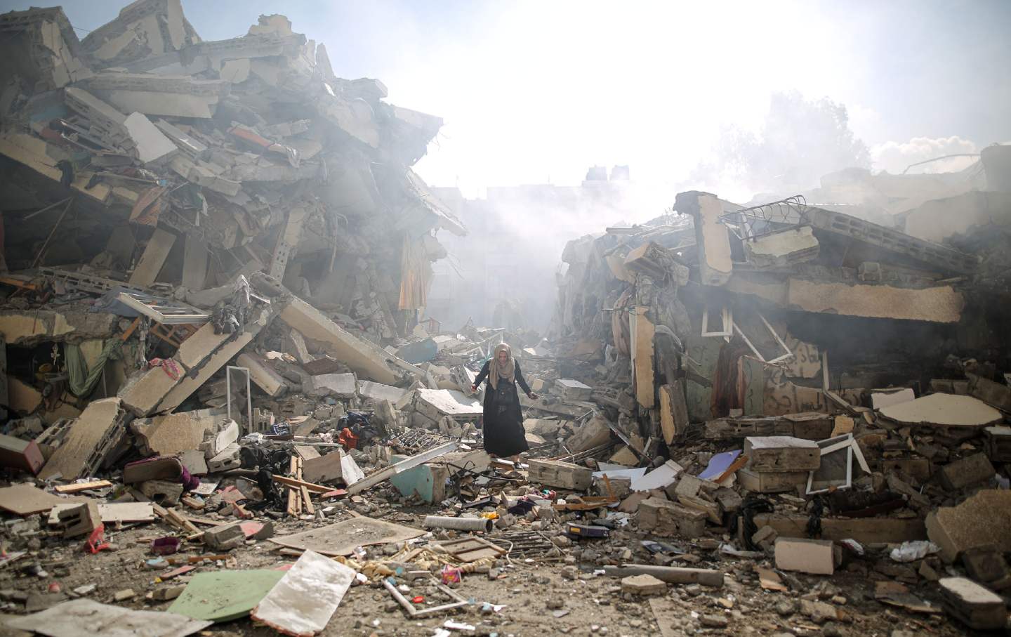 A woman walks amid the rubble of residential buildings destroyed by Israeli air strikes in the al-Zahra neighborhood of the Gaza Strip on October 19, 2023.