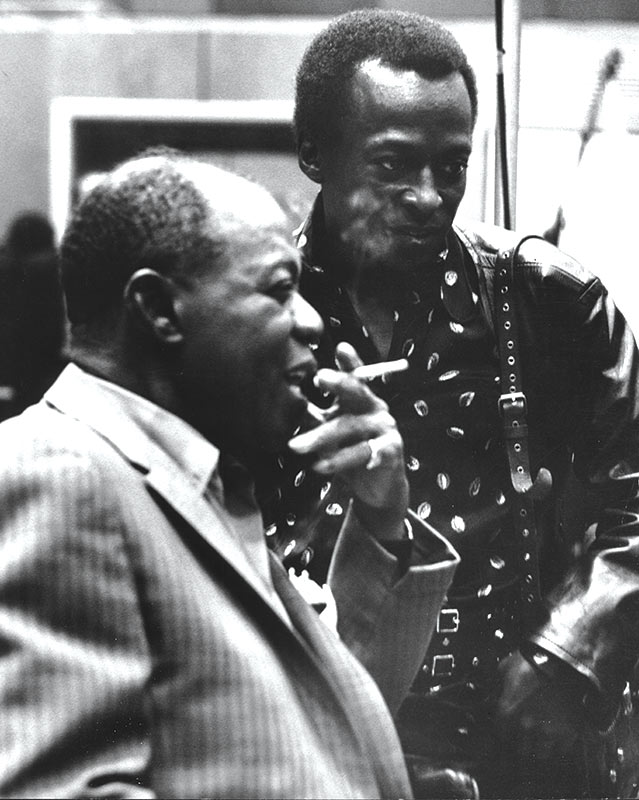 Louis Armstrong and Miles Davis talk in the studio in 1970.