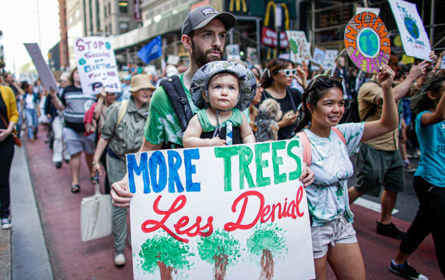 family, two adults and a baby, marching in climate strike new york city
