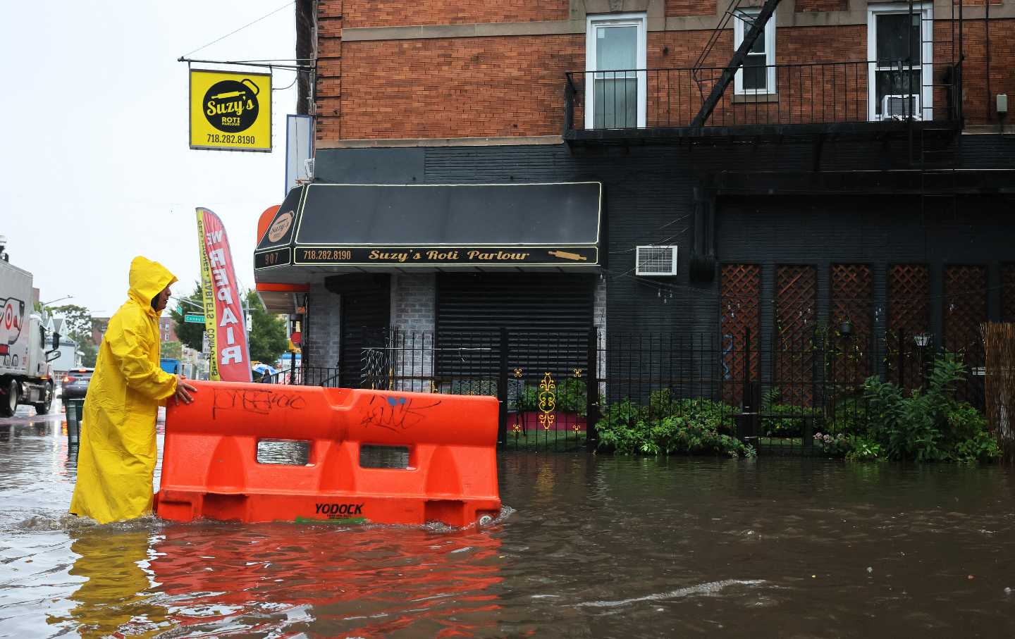 A person pushes a barricade floating on a flooded street amid a coastal storm on September 29, 2023, in the Flatbush neighborhood of Brooklyn, N.Y..