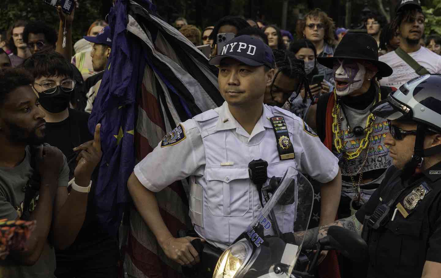 A police officer stands in front of demonstrators during the March for Trans Revolution in Washington Square Park in New York, 2023.